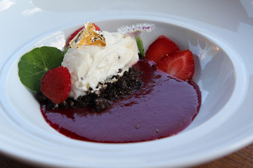 Japanese desserts decorated with fruit, flowers and whipped cream with gold leaf on top.