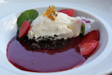 Japanese desserts decorated with fruit, flowers and whipped cream with gold leaf on top.