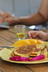 Pancake decorated by red dragon fruit and mango on top in yellow plate.