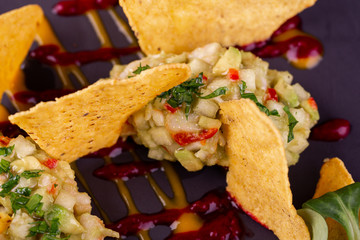 Guacamole with avocado and chopped greens, served with chips, ketchup and mustard