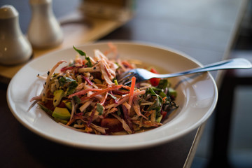 Vegan delicious salad with avocado and other vegetables and herbs.