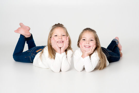 ni&ntilde;as felices tumbadas en el suelo estudio fondo blanco