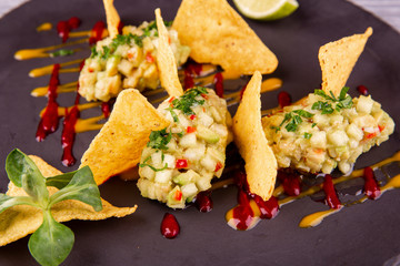 Guacamole with avocado and chopped greens, served with chips, ketchup and mustard