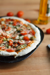 homemade pizza with sausage and cherry tomatoes close-up on a wooden table. culinary concept