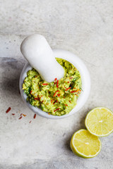 Cooking guacamole - avocado sauce in a white stone mortar, top view.