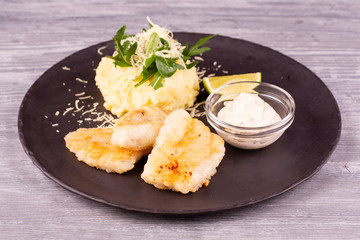 Cod fillet fried, served with mashed potatoes, grated cheese and cream sauce with chopped greens