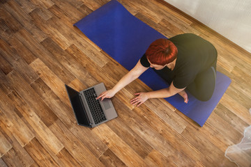 Adult girl practice online yoga lesson at home during quarantine isolation during the coronavirus...