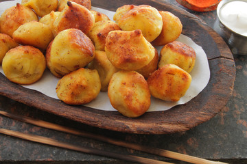 
fried ravioli on a wooden plate and served on a marble table with sauce and spices.