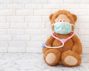 teddy bear with medical mask and stethoscope isitting in hospital
