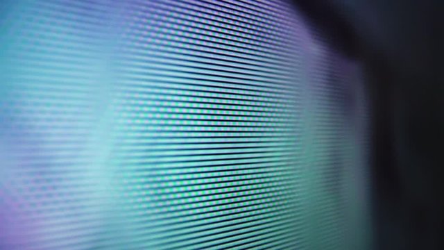 Macro view: light blue glowing pixels on LCD screen of new TV with playing movie in light room extreme close view