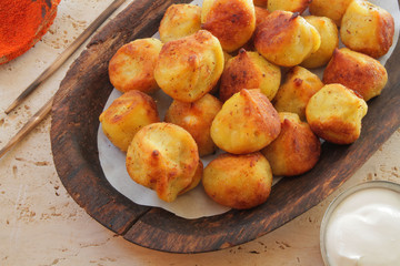 
fried ravioli on a wooden plate and served on a marble table with sauce and spices.