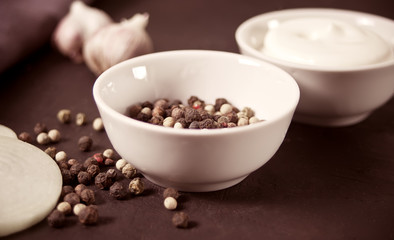 Mixed peppers red, black, white in a white small bowl.