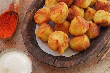 
fried ravioli on a wooden plate and served on a marble table with sauce and spices.