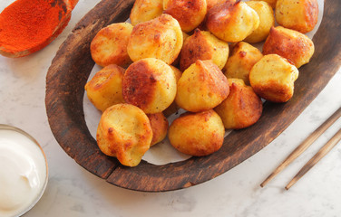 
fried ravioli on a wooden plate and served on a marble table with sauce and spices.