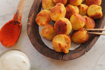 
fried ravioli on a wooden plate and served on a marble table with sauce and spices.