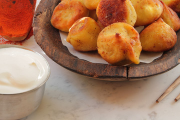 
fried ravioli on a wooden plate and served on a marble table with sauce and spices.