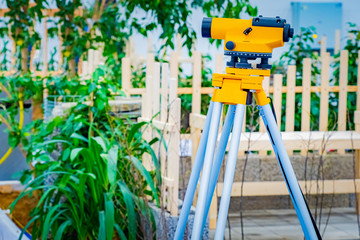 Theodolite on the background of the front garden. Optical level. Geodetic measurements....