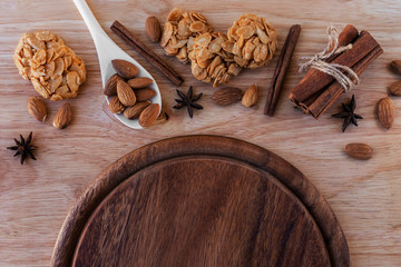 Almond cookies, bunch of cinnamon and almonds with star anise flowers, white wooden spoon, on a light brown wooden board and a brown board below. Great background for a cafe or restaurant menu