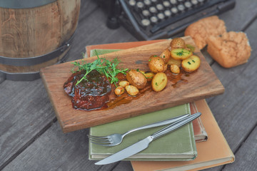 steak with potatoes and herbs on a wooden board