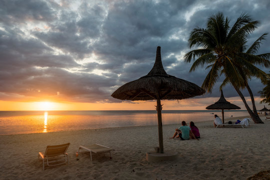 Couple watching sunset on the beach at Flic en Flac, Mauritius