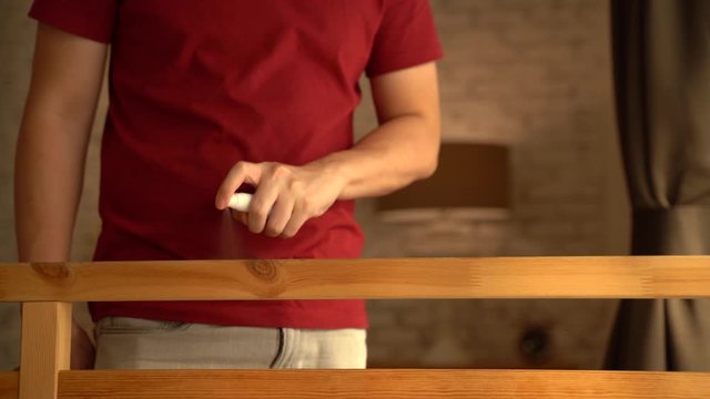 Close-up of human hands using alcohol sanitizer to clean furniture to avoid Coronavirus inflection spread through droplets. Corona Virus (Covid 19) disease protection concept.