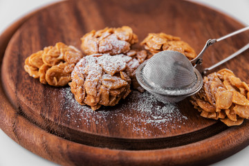 Almond cookies sprinkled with icing sugar on top with a strainer with icing sugar on a dark brown wooden board on a white background. Great background for a cafe or restaurant menu, signboard.