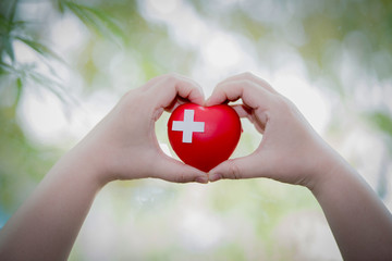 A close up shot of a girl holding a medical sign, red first aid, Red Cross concept