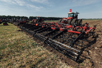 red tractor with a plant for tillage during summer plowing