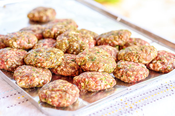 Raw homemade kebab or meatball with green parsley, garlic, spiced and sliced onion in tray on table. It is a very popular in Middle East. BBQ outdoor party.