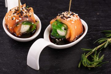 Canape salmon with cheese and sesame seeds on black background