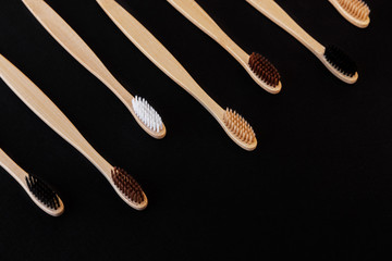 Group of eco bamboo toothbrushes, on black background. Different color. Top view, copy space. Natural organic product for oral hygiene. Dental zero waste and no plastic concept. Safe for the earth.