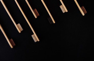 Group of eco bamboo toothbrushes, on black background. Different color. Top view, copy space....