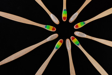 Group of white and rainbow eco bamboo toothbrushes, on black background. Top view. Natural organic...