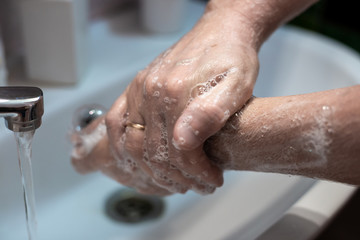 Fototapeta premium man washes his hands with liquid soap over a sink at home