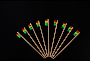 Pride fan. Group of rainbow eco bamboo toothbrushes, on black background. Top view, copy space. Natural organic product for oral hygiene. Dental zero waste and no plastic concept.