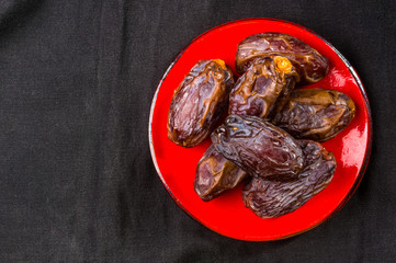 Big luxury dried date fruit in bowls on the dark surface, kurma ramadan kareem concept, close up.