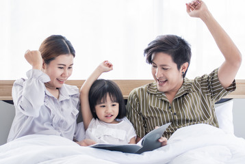 Dad and mom are reading bedtime stories to daughter