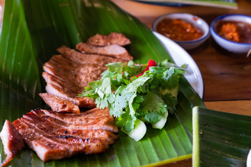 Close up juicy yummy fried sliced pork on green banana leaf , popular traditional thai food.