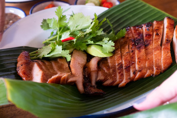 Close up juicy yummy fried sliced pork on green banana leaf , popular traditional thai food.