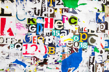 Torn and peeling pieces of paper on colorful collage from clippings with letters and numbers texture background.