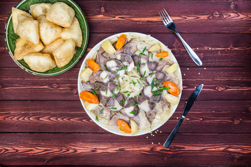 Beshbarmak dish with baursak - traditional Kazakh Asia food and national bread. Noodles with lamb and onion close-up on a plate on the table. Horizontal top view