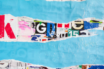 Torn shabby and peeling blue paper poster on colorful collage from clippings with letters and...