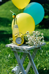 set yellow green. concept idea with balloons , lemonade, flowers chamomile and clock on the wood chair.  background for shooting . fun idea, beautiful set, quality and luxury time. on green grass