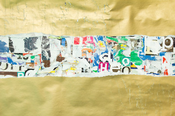 Torn, crumpled and scratched golden glossy paper placard glued on old ripped and peeling pieces of paper posters background.
