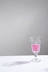 bebida rosa en copa de vino con fondo gris minimalista