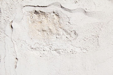 Old white cracked wall with big dent, rough surface and peeling paint texture background.
