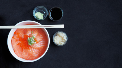 Top View and focus on Salmon with Japanese rice or Salmon Ikura Don in paper dish from delivery restaurant on black Table cloths