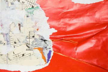 Torn and crumpled glossy red poster on old scraps of paper music sheet with notes background.