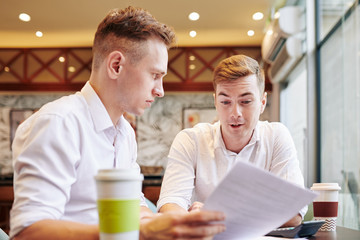 Serious young business people meeting in cafe to discuss contract details