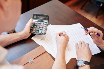 Business people working with documents and calculating sum of revenue for last month